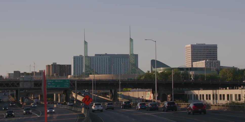Driving point-of-view on a Portland, Oregon highway emerges from under an overpass to reveal the Convention Center and city skyline