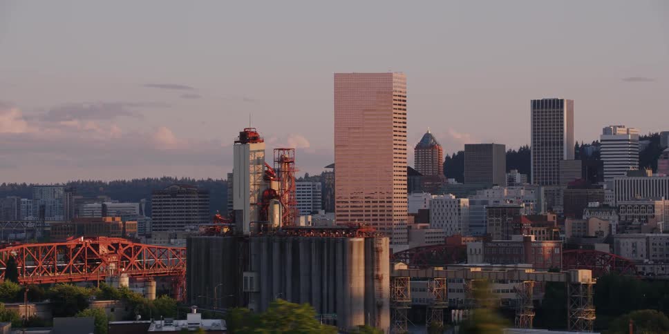 A beautiful tracking shot reveals the Portland, Oregon city skyline, including the Broadway Bridge and downtown skyscrapers, glowing at sunset