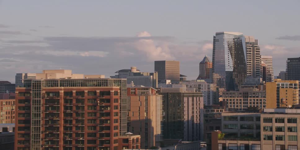 Slow-motion aerial shot pans across the diverse architecture of a modern city skyline at golden hour