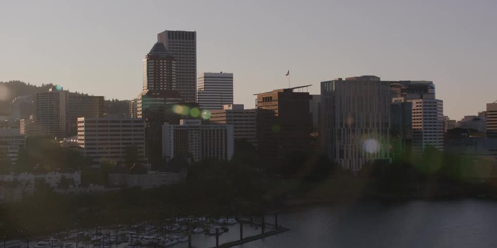 A slow zoom shot captures the Portland, Oregon skyline and a marina on the Willamette River during a beautiful, hazy sunrise