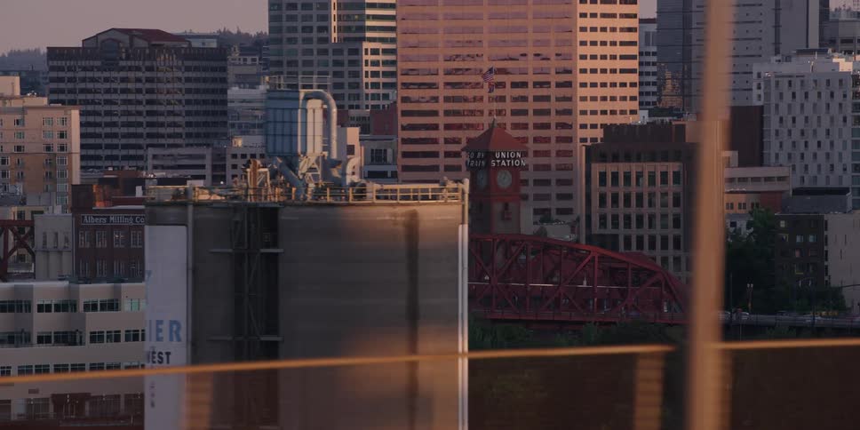 A slow aerial shot moves past the Portland, Oregon skyline featuring the Broadway Bridge during a beautiful golden hour sunset