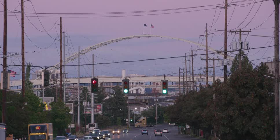 A slow push-in shot down an industrial city street towards the Fremont Bridge in Portland, Oregon at dusk under a purple sky