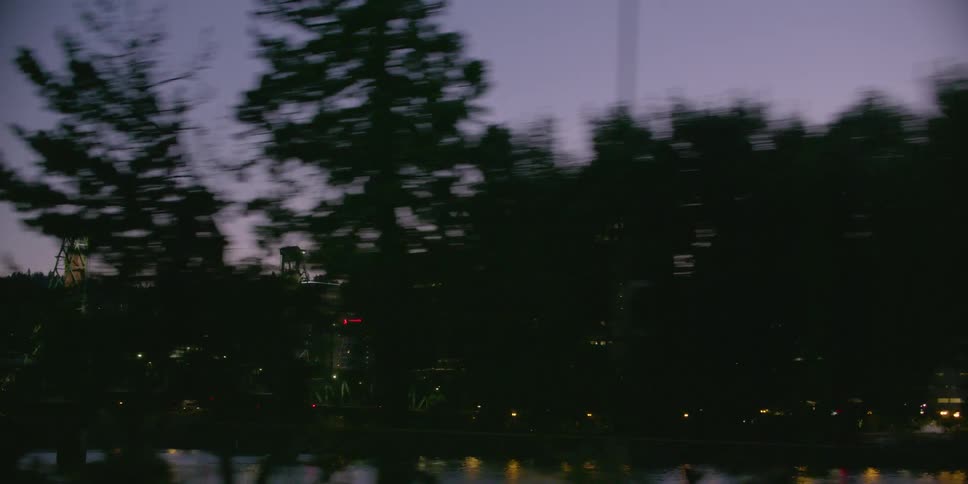 Driving past the illuminated Hawthorne Bridge and Portland, Oregon skyline at dusk