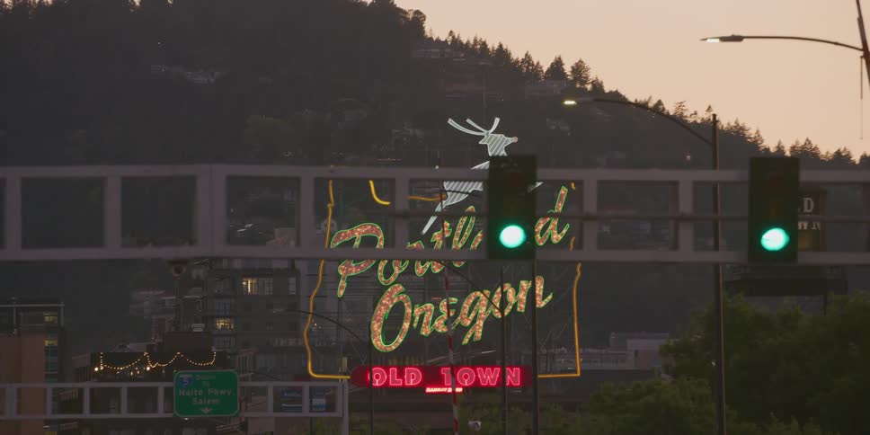 The iconic Portland, Oregon sign flickers to life at dusk, casting a colorful glow over the city