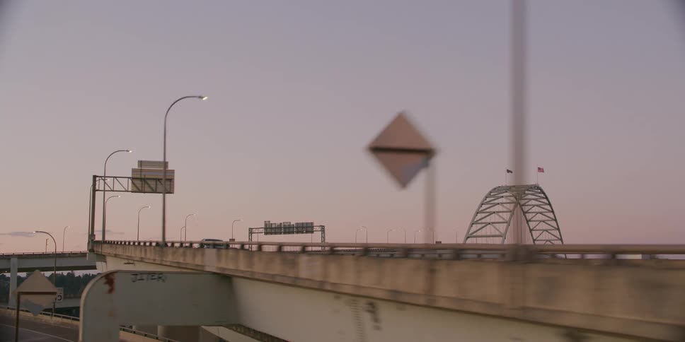 Tracking shot from a moving vehicle reveals Portland's Fremont Bridge and highway system against a beautiful dusk sky