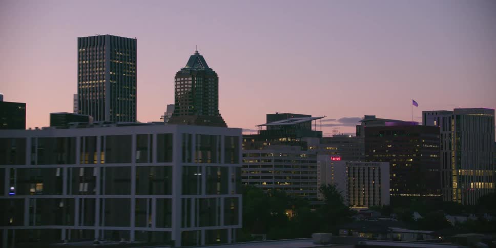 A smooth tracking shot reveals the Portland, Oregon city skyline with illuminated buildings against a beautiful twilight sky