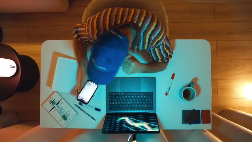 Top-down time-lapse of a dedicated trader analyzing stock market trends and making notes at his desk late into the night