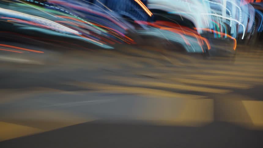 An abstract motion blur time-lapse captures the chaotic energy of a busy city intersection at night