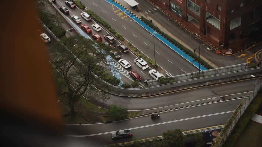 High-angle view of a traffic jam on a wet city street as other cars and motorcycles drive by