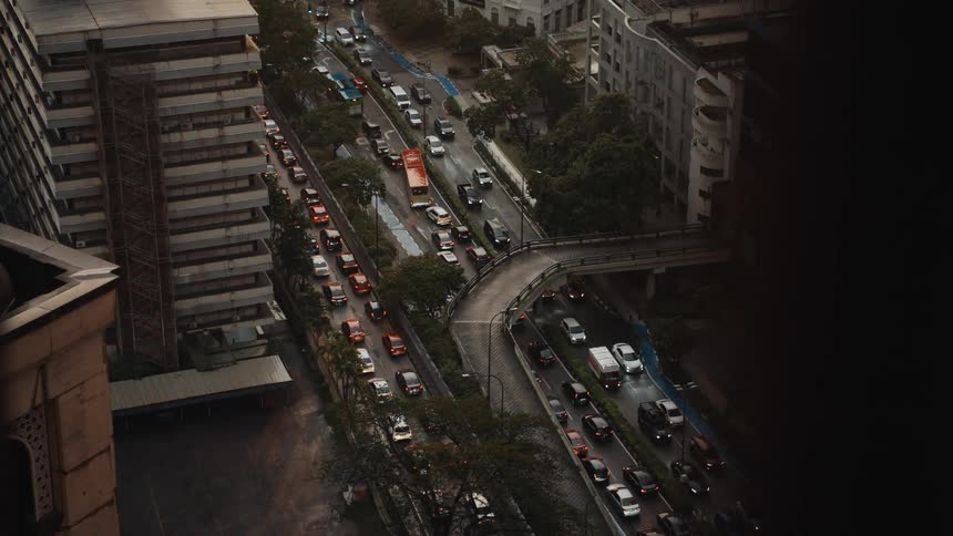 A high-angle view from a skyscraper captures congested city traffic on a rainy and overcast day