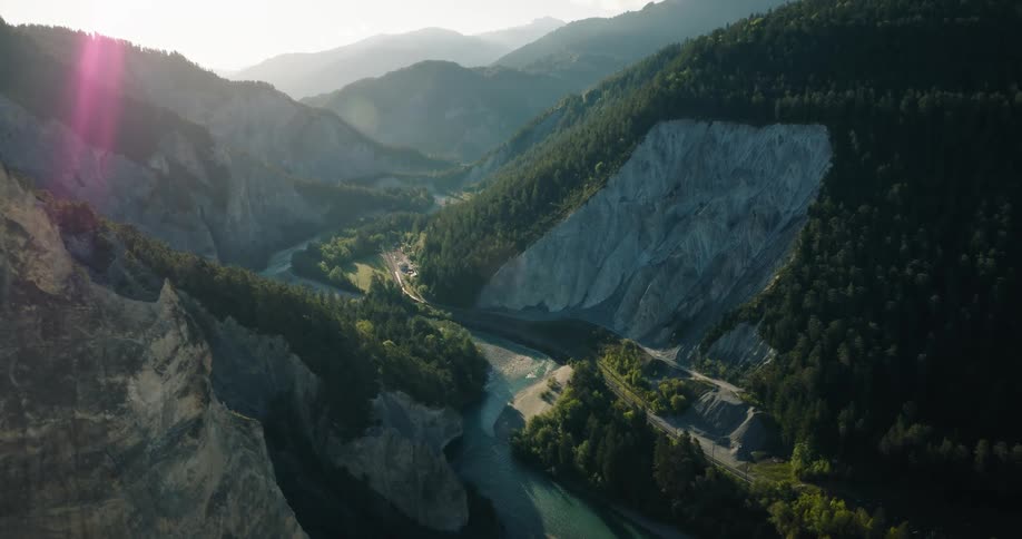 Aerial view of a dramatic river canyon winding through forested mountains at sunrise