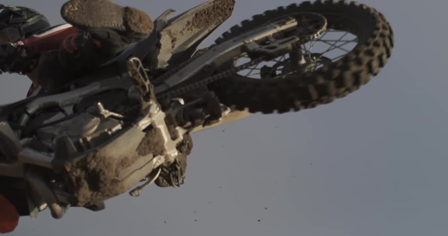 Low angle super slow motion shot of a motocross rider flying through the sky during a jump