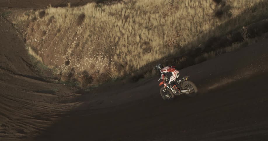 High angle slow motion view of a motocross rider navigating a sharp turn on a dirt course