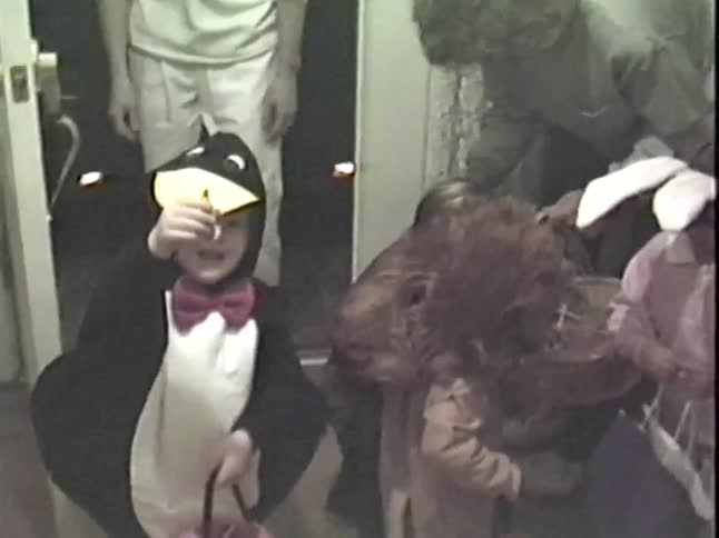 Vintage VHS footage shows adorable children in animal costumes trick-or-treating for Halloween candy