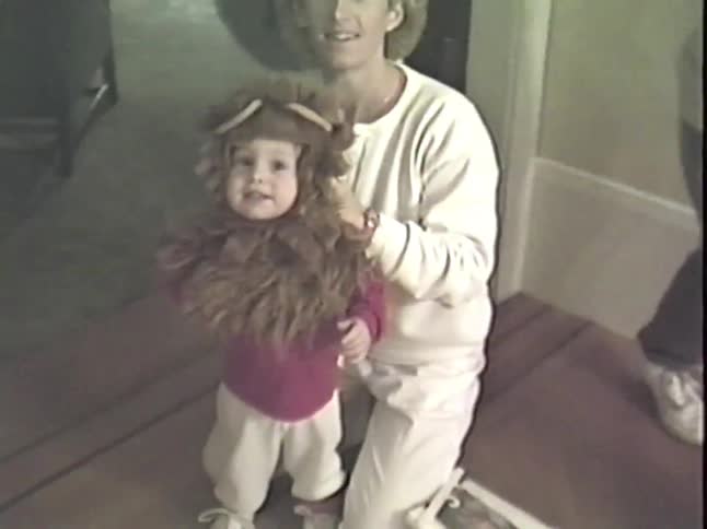 A mother helps her adorable toddler into a lion costume for Halloween in a nostalgic home video from the 1980s