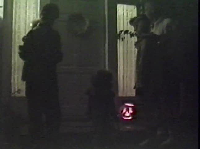 Vintage footage shows a family with young children in costume trick-or-treating on Halloween night