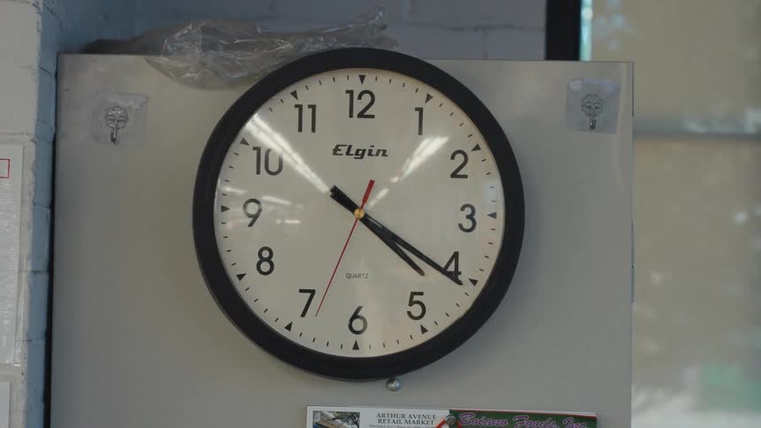 A slow zoom into a classic analog wall clock showing the time as the second hand ticks