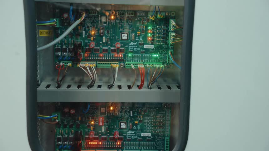A close-up view of an electronic control panel with circuit boards and flashing indicator lights