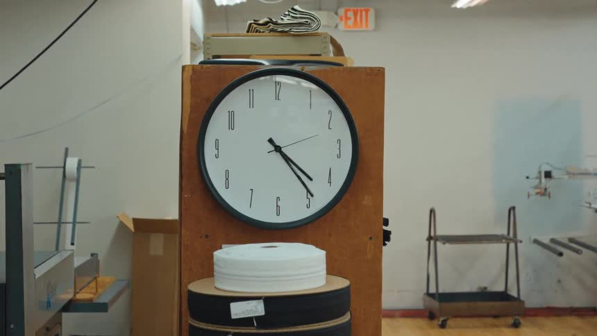 An analog clock on a wooden stand in a factory slowly zooms into focus