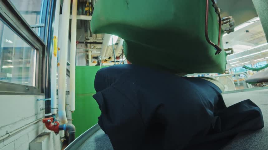 A unique point-of-view shot from a garment as it is positioned and then steamed by an industrial press in a clothing factory
