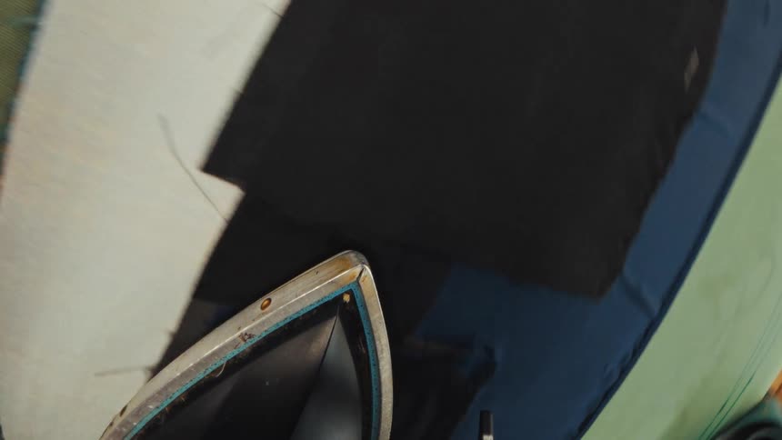 A unique point-of-view from an iron as a tailor steams and presses pieces of fabric in a workshop