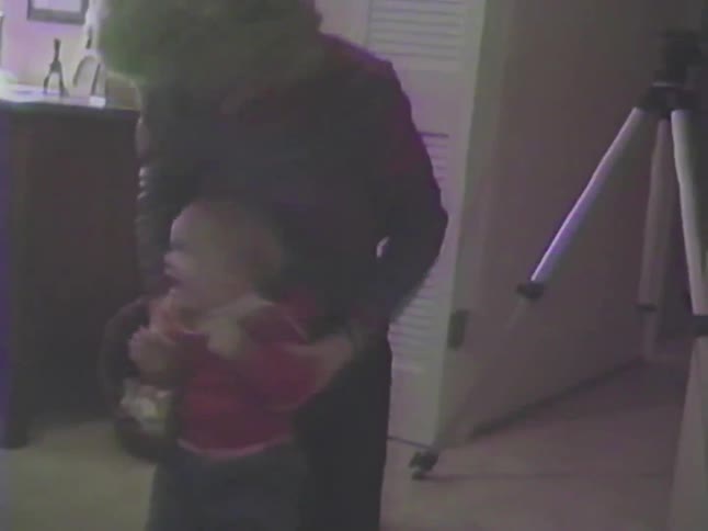 A family plays with their energetic baby on the floor in a vintage 1980s home video