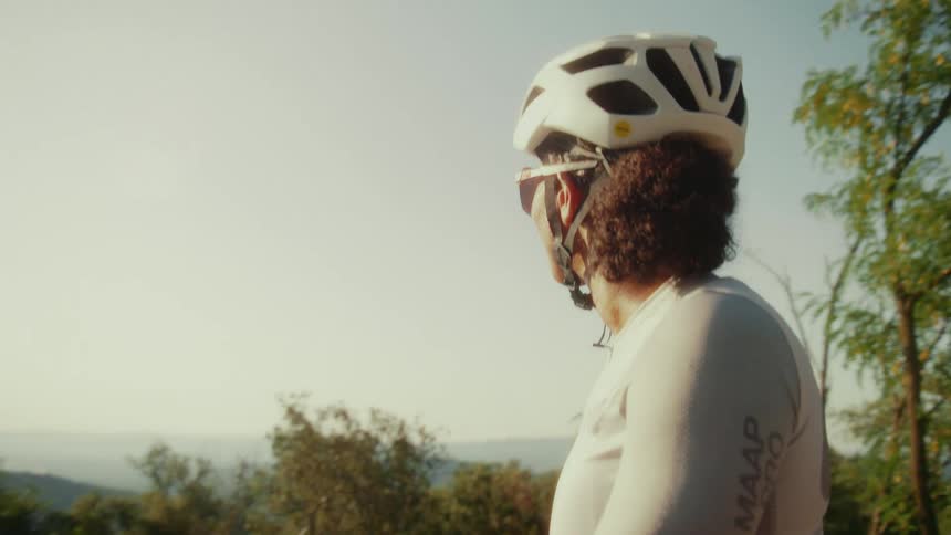 A female cyclist in full gear pauses her ride to contemplate the beautiful scenic view on a sunny day