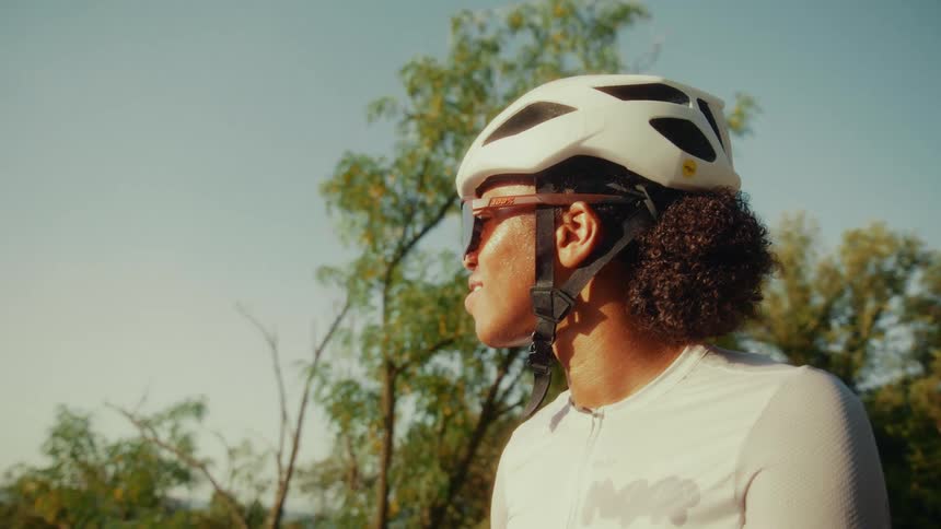 Side profile of a female cyclist in a white helmet and sunglasses enjoying the view on a sunny day