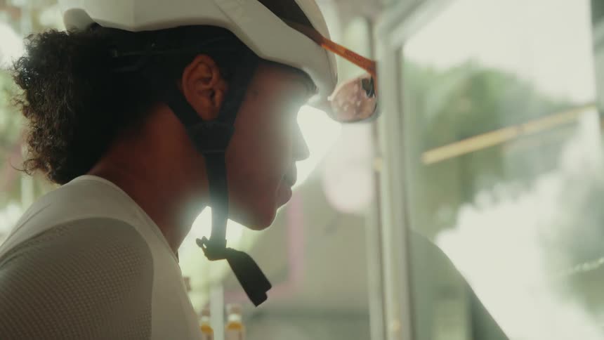 Side view close-up of a female cyclist in a helmet looking into a store window after a ride