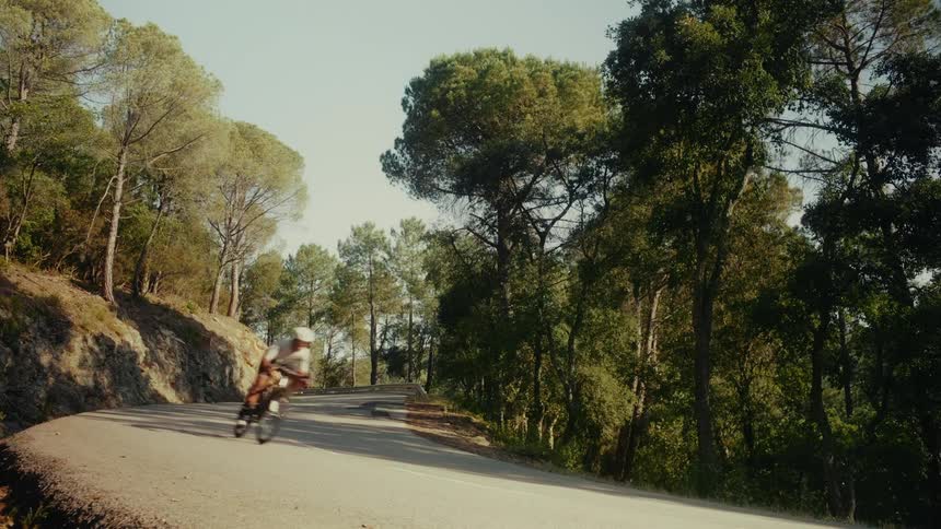 Motion blur shot of a cyclist speeding down a winding forest road on a sunny day