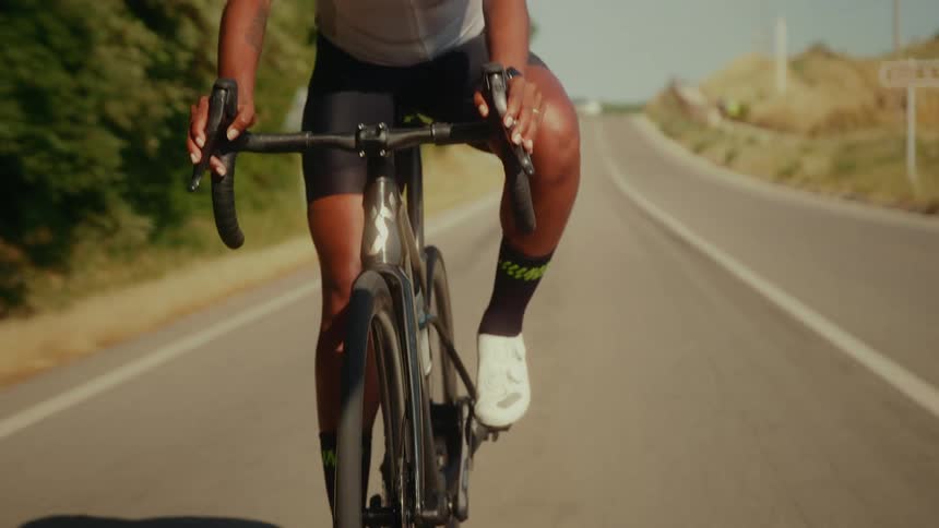 Front view close-up of a female athlete riding her road bike down a paved country road on a sunny day