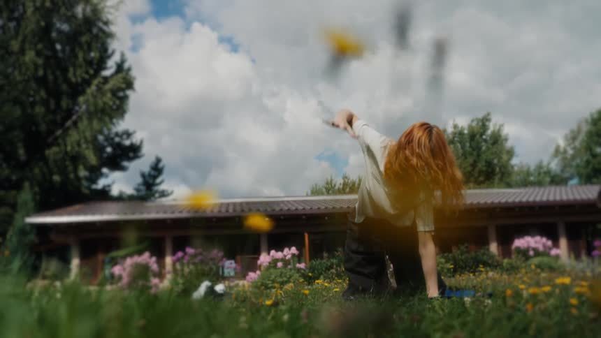A red-haired woman gracefully practices a yoga routine in a serene, sunlit garden filled with colorful flowers