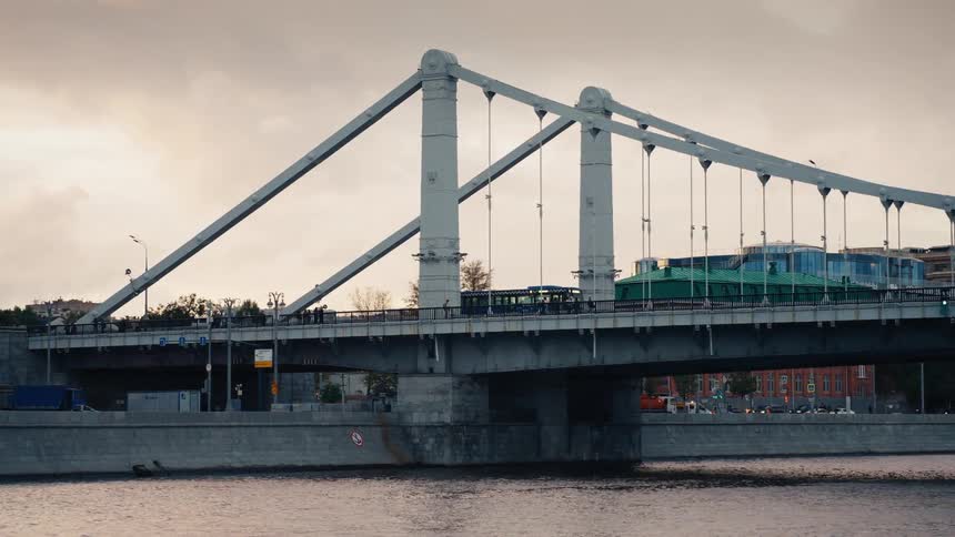 Traffic crosses the iconic Crimean Bridge in Moscow as the city skyline sits under a cloudy, warm sky