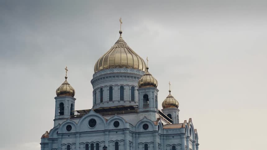 The majestic Cathedral of Christ the Saviour with its golden domes stands against a grey, cloudy sky in Moscow