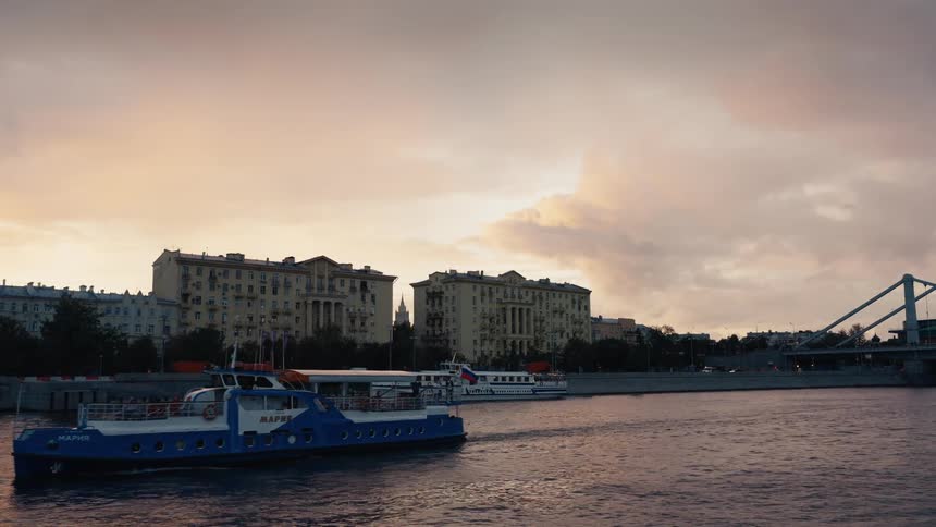 A scenic view of a tour boat cruising down the Moscow River in Russia against a beautiful golden hour sunset