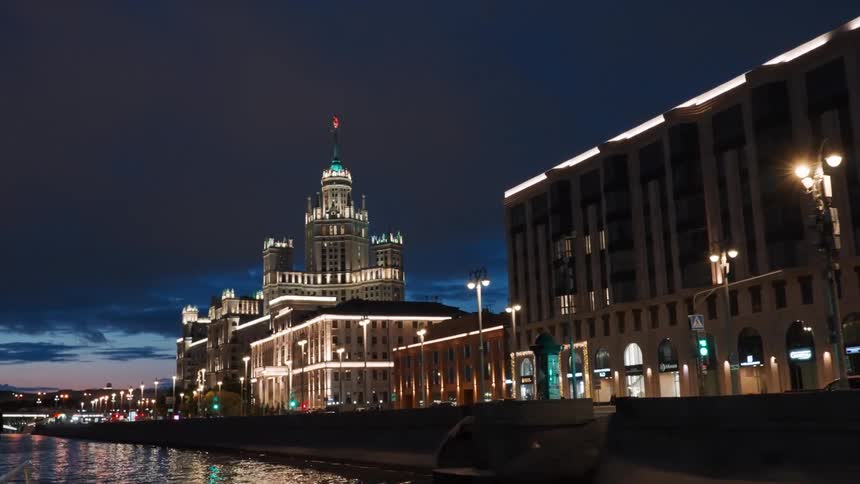 A majestic view from a boat on the Moskva River reveals the iconic Kotelnicheskaya Embankment Building illuminated at twilight