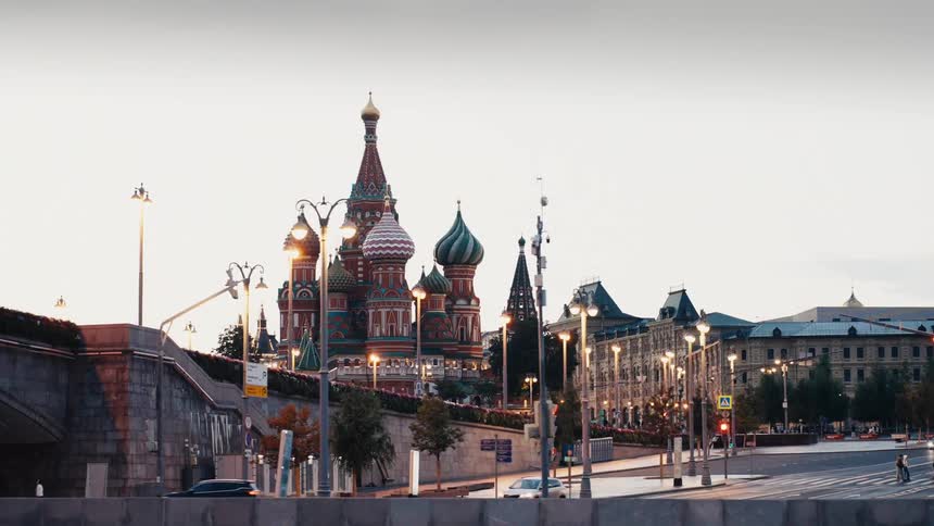 A slow dolly shot reveals the iconic St. Basil's Cathedral on Red Square in Moscow, Russia, as the city lights begin to glow at twilight