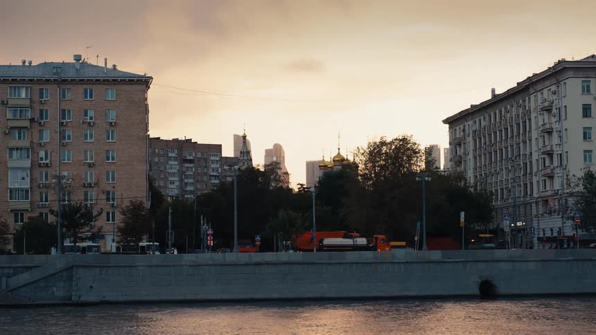 View from a river boat in Moscow captures the contrast between old apartment buildings and modern skyscrapers against a warm sunset sky