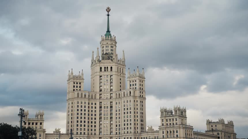The historic Kotelnicheskaya Embankment Building in Moscow stands against a dramatic, cloudy sky