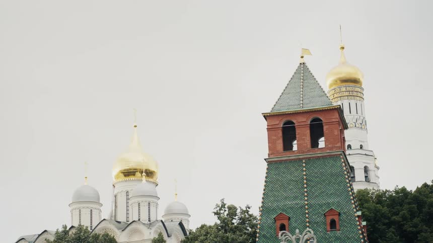 A slow pan shot reveals the iconic golden domes and towers of the historic Moscow Kremlin against an overcast sky