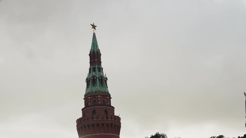 A slow zoom towards a Moscow Kremlin tower topped with a red star against a gloomy, overcast sky in Russia