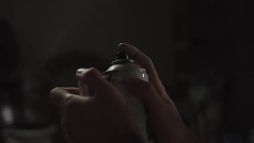 A person creates a flamethrower by igniting the aerosol from a spray paint can with a lighter in slow motion