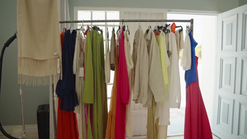 A clothing rack filled with a vibrant collection of women's dresses and apparel in a brightly lit room