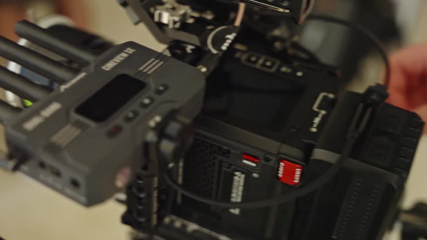 Close-up of a camera operator setting up and adjusting cables on a professional cinema camera rig
