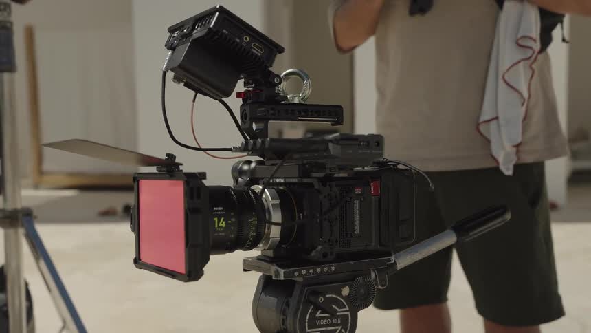 A professional cinema camera rigged up on a tripod on an outdoor film set