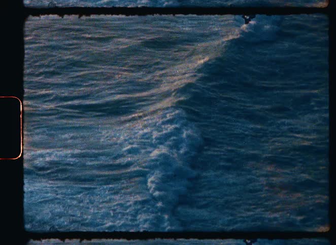 Authentic Super 8 film footage captures a close-up of deep blue ocean waves moving in slow motion