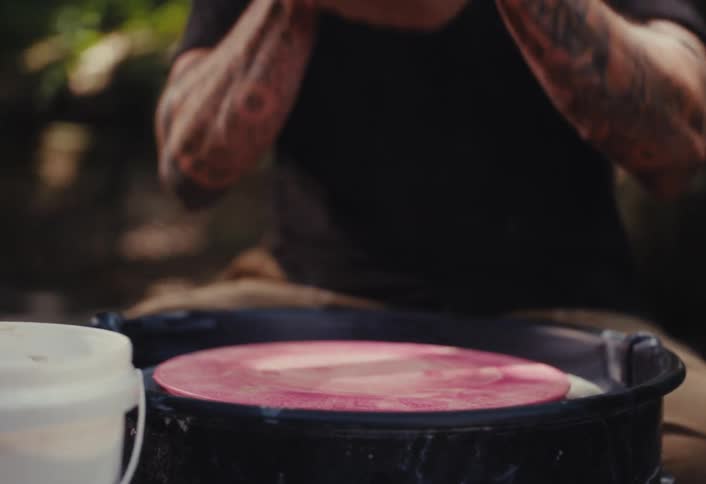 A potter kneads a lump of clay and centers it on a pottery wheel to begin sculpting