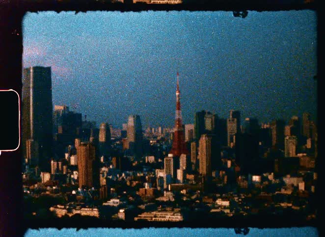 A grainy, vintage handheld shot of the Tokyo Tower and the expansive city skyline at dusk