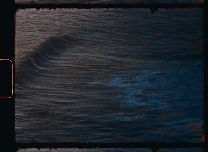 Vintage Super 8 film footage shows ocean waves rolling in slow motion during a beautiful sunset