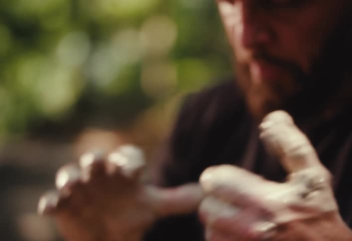 A close-up slow-motion shot of a potter's hands shaping clay on a wheel, with the focus shifting to the artisan's face